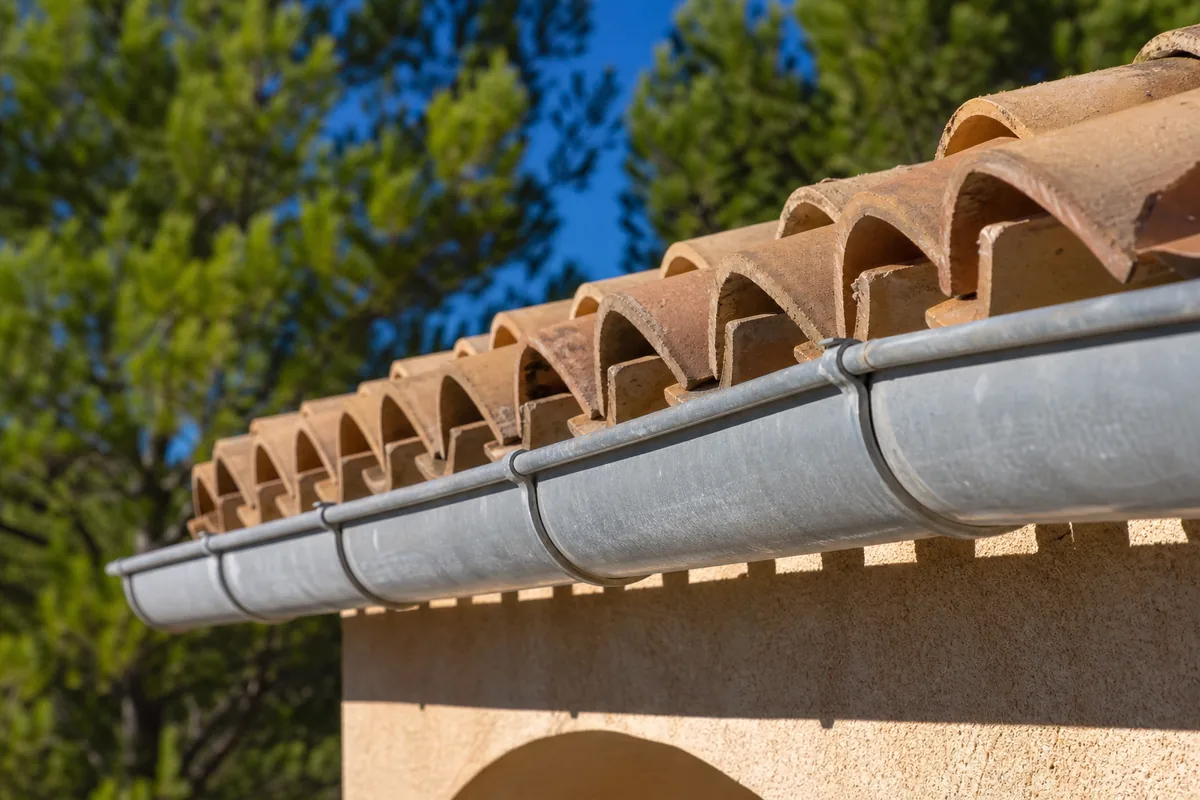 Toiture de villa en tuile romane à Cagnes-sur-Mer avec gouttière en zinc et pins d’Alep en arrière-plan