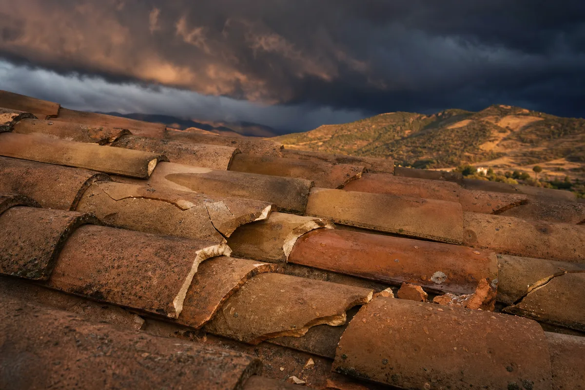 Pan de toiture en tuile canal ocre d’une bastide du Var intérieur sous un ciel d’orage qui se lève